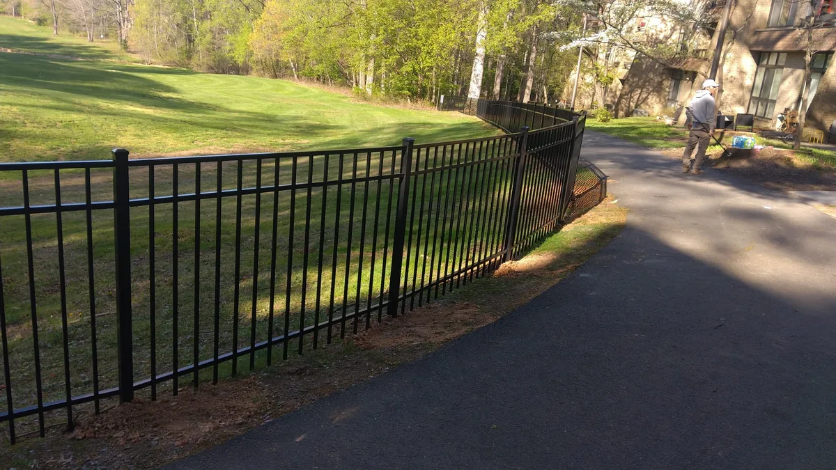 Black aluminum fence following a sloped lawn, under Our Fencing Projects
