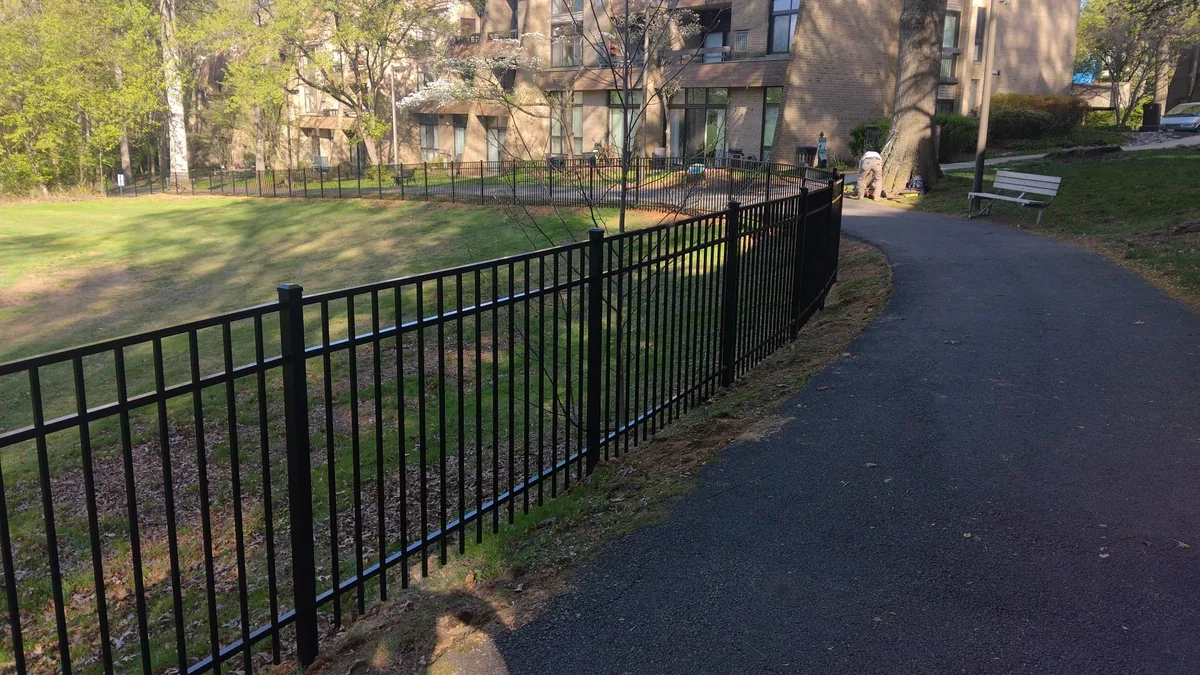 Black aluminum fence along a park walking trail, under Our Fencing Projects