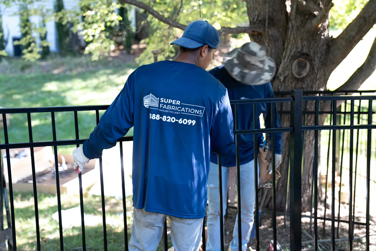 Crew member aligning a black aluminum fence panel, under Our Fencing Projects