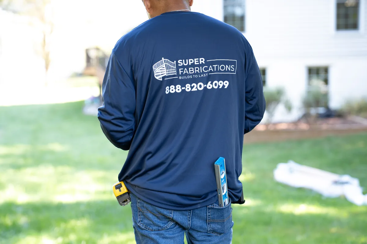 Crew member fastening hardware on a black aluminum gate, under Our Fencing Projects