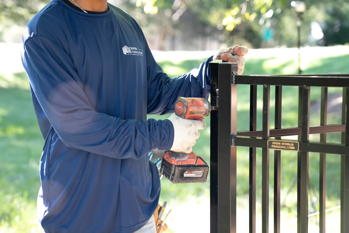 Super Fabrications crew hanging a black aluminum fence panel, under Our Fencing Projects