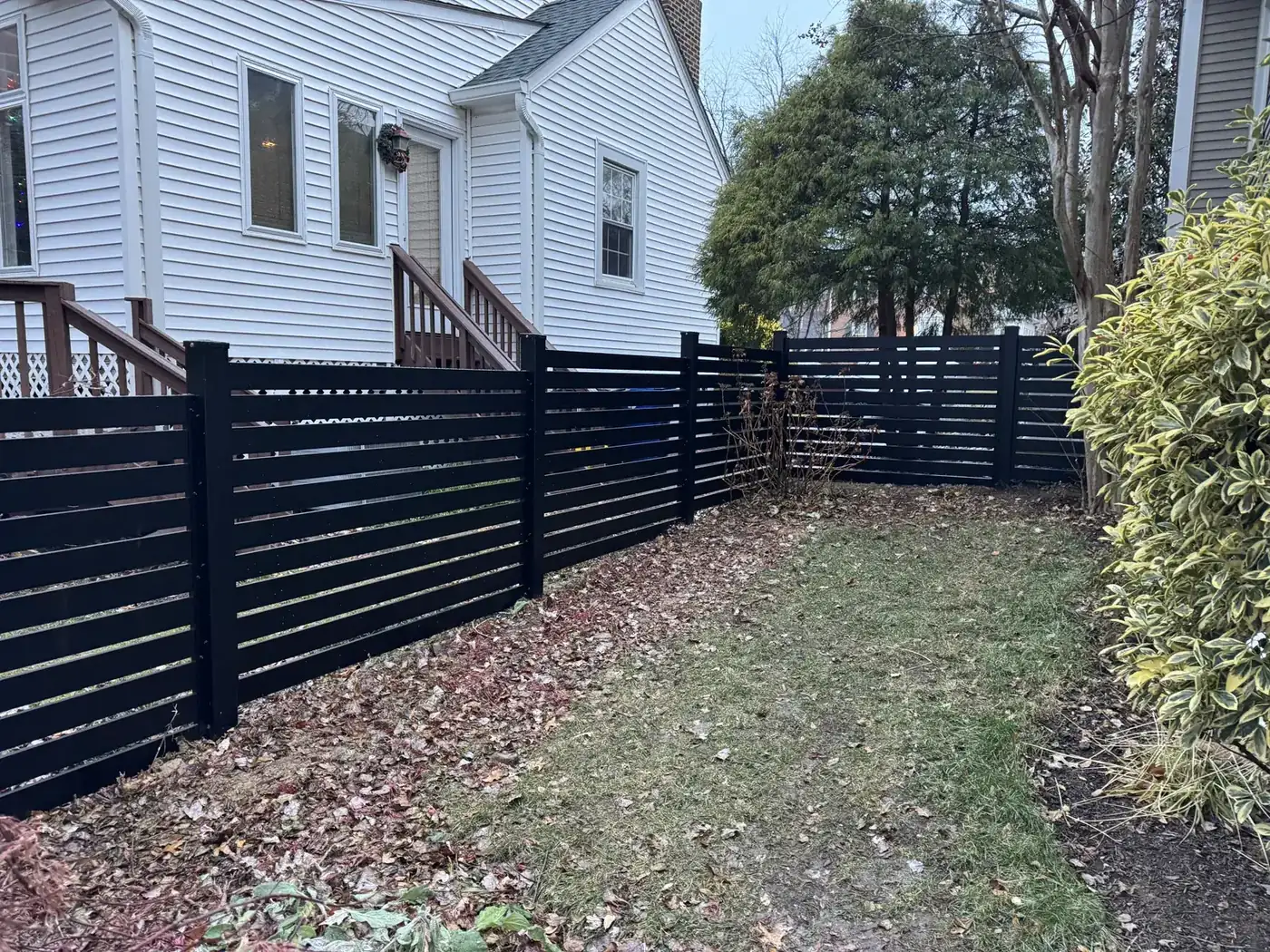 Black horizontal aluminum privacy fence along a house, under Our Fencing Projects