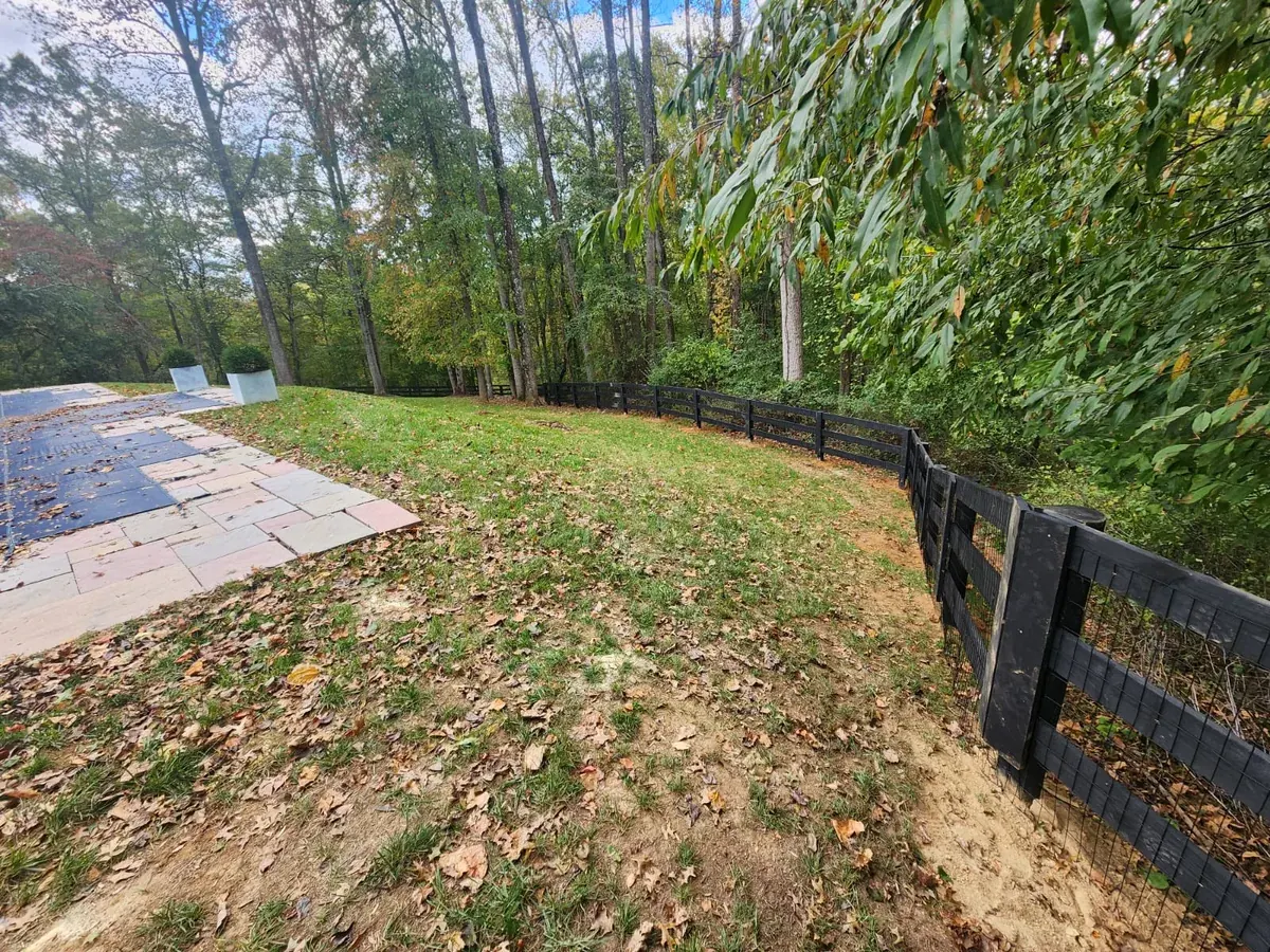 Black ranch rail with a field gate, under Our Fencing Projects