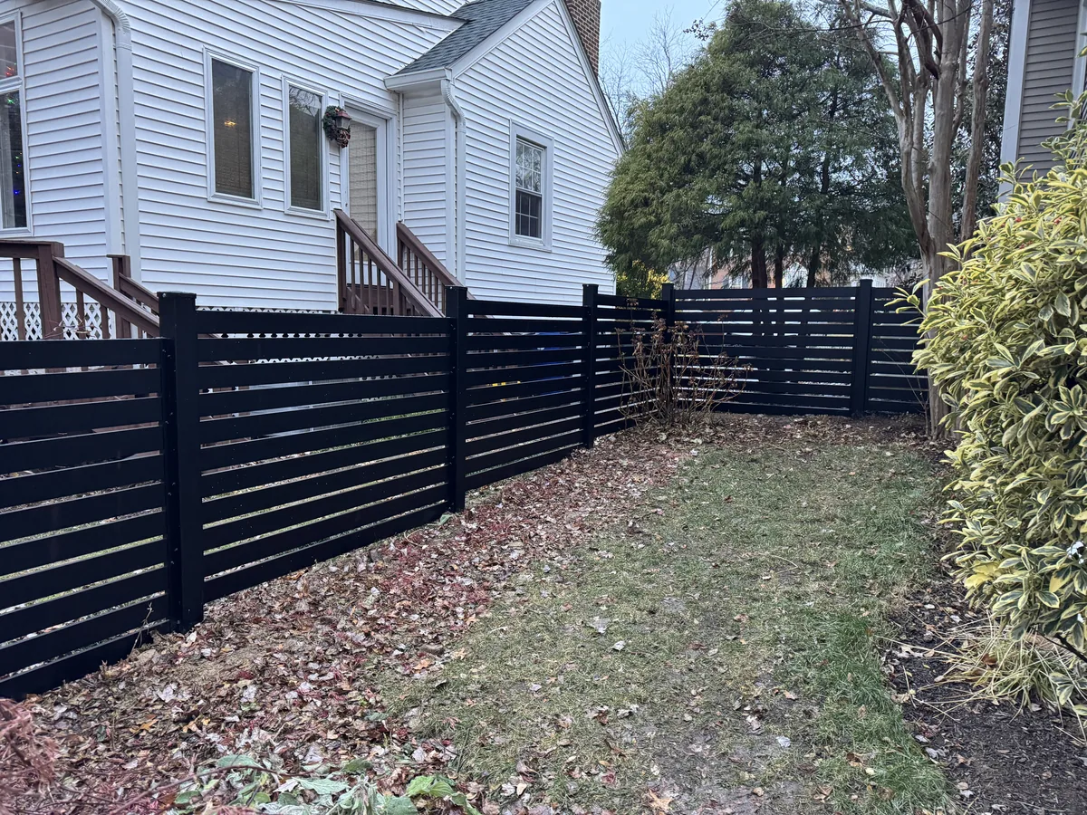 Sleek black aluminum fence with thin pickets beside a patio, under Our Fencing Projects
