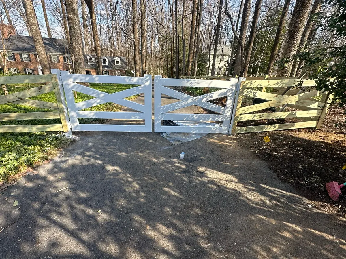 White crossbuck wood farm gate across a gravel drive, under Our Fencing Projects