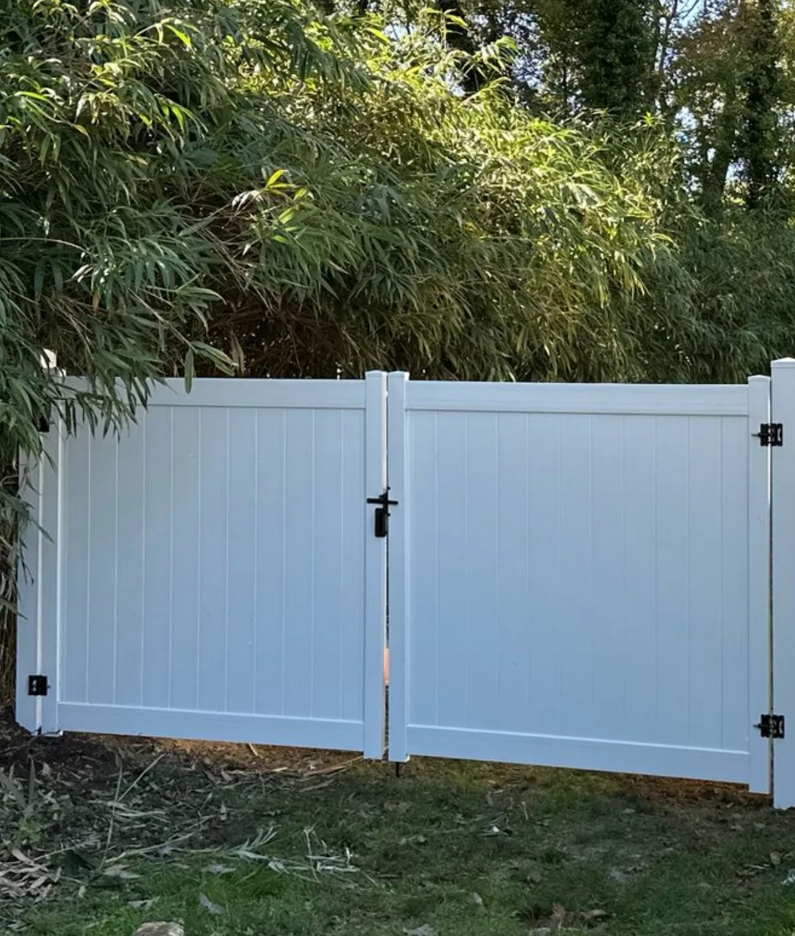 White vinyl privacy gate set between trees, under Our Fencing Projects
