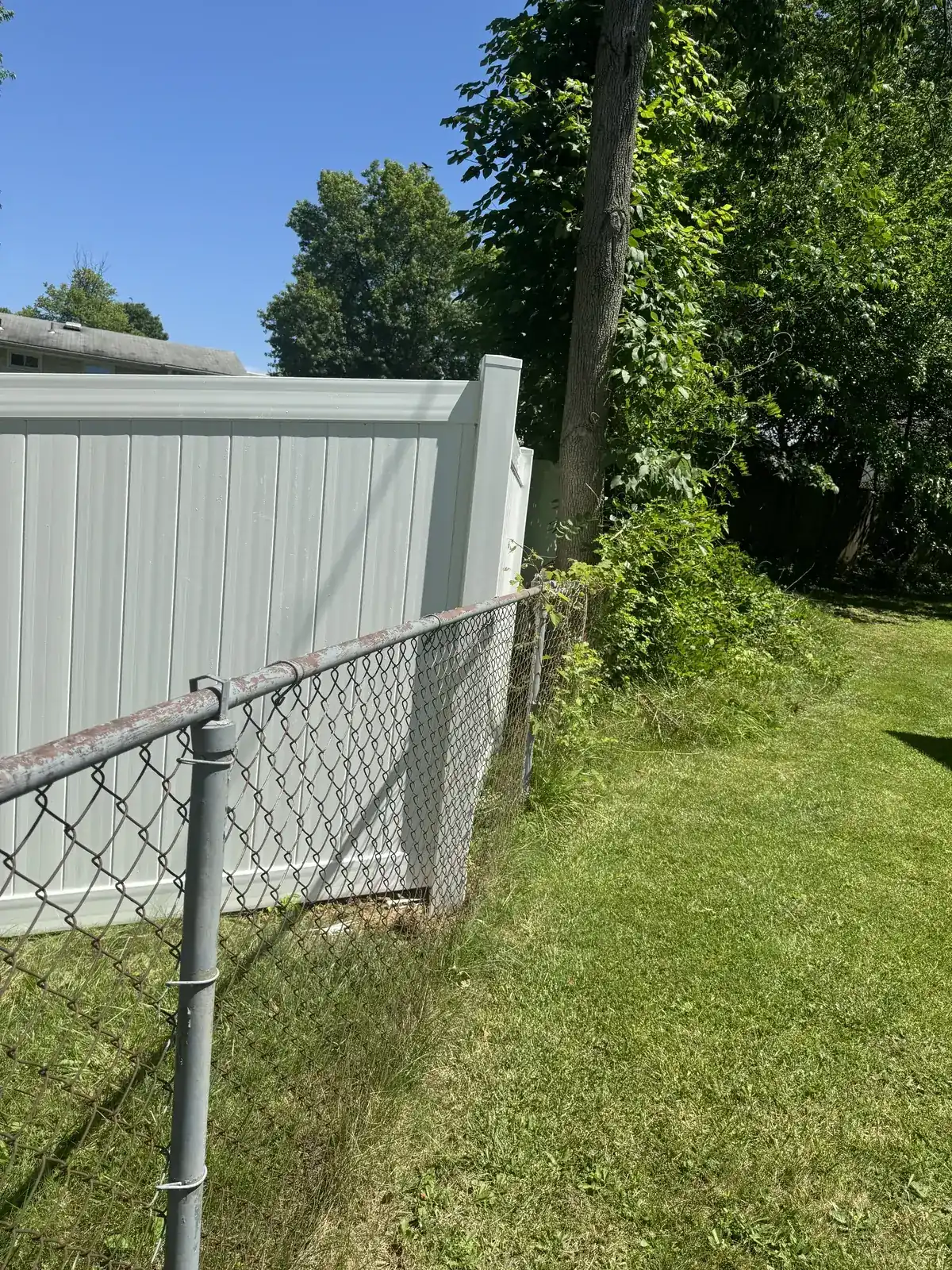 White vinyl privacy fence enclosing a backyard, under Our Fencing Projects