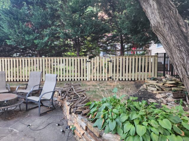 a wood fence and chairs in a backyard