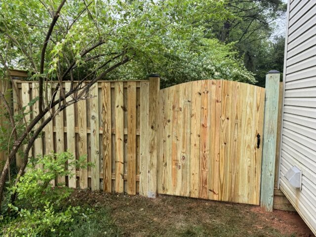 a shadowbox wooden fence with a tree in the background