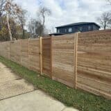 a cedar wood fence horizontal with a house in the background