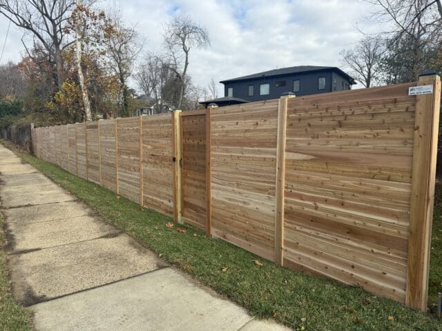 a cedar wood fence horizontal with a house in the background